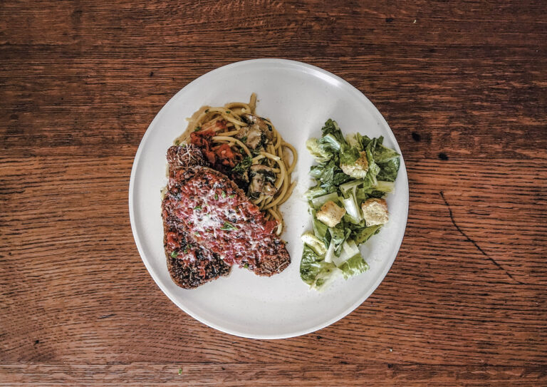 Sunday Eggplant Parmesan served over a bed of creamy pasta.