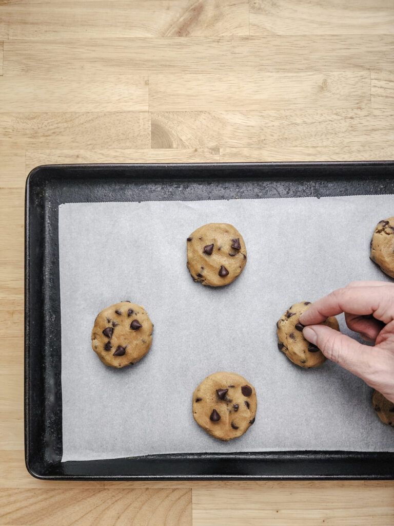 Placing chocolate chips on top of cookies before baking