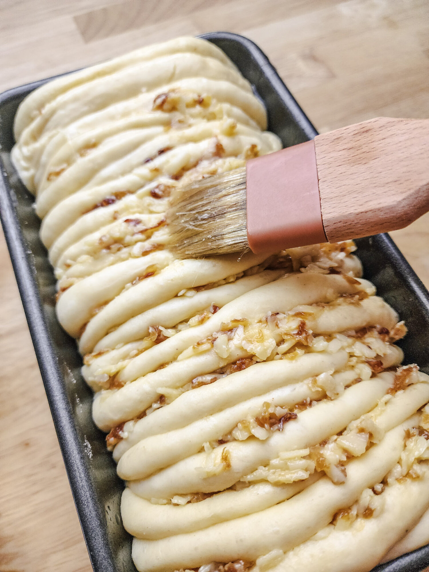 Spreading egg wash on the French Onion Pull Apart Bread before baking.