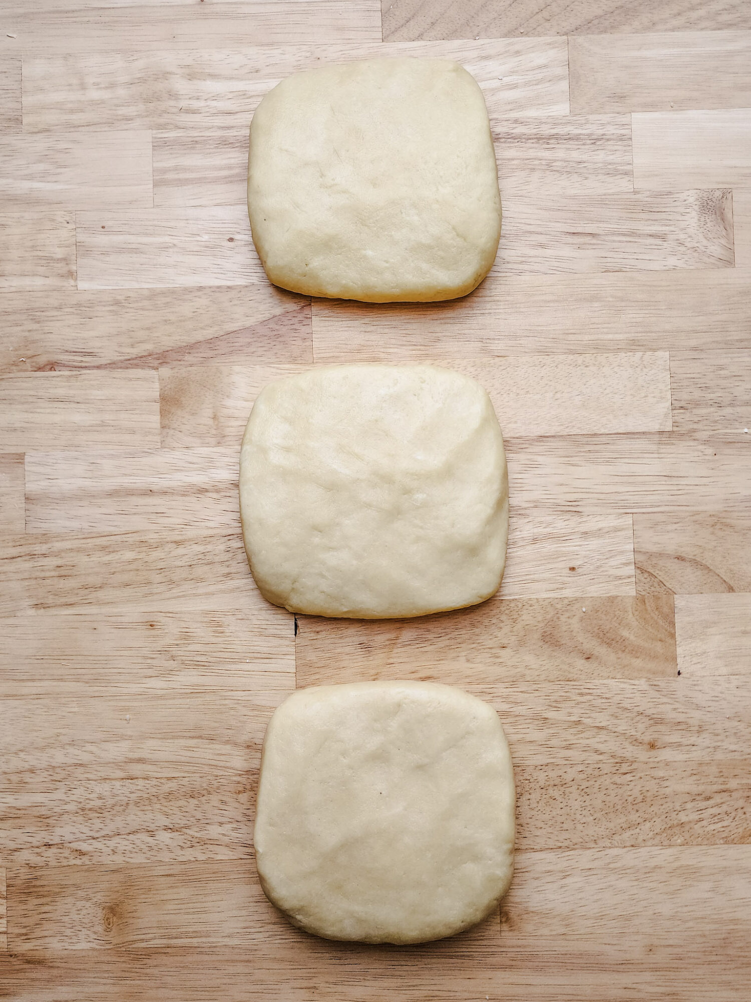 Kolaczki dough divided into three equal pieces.