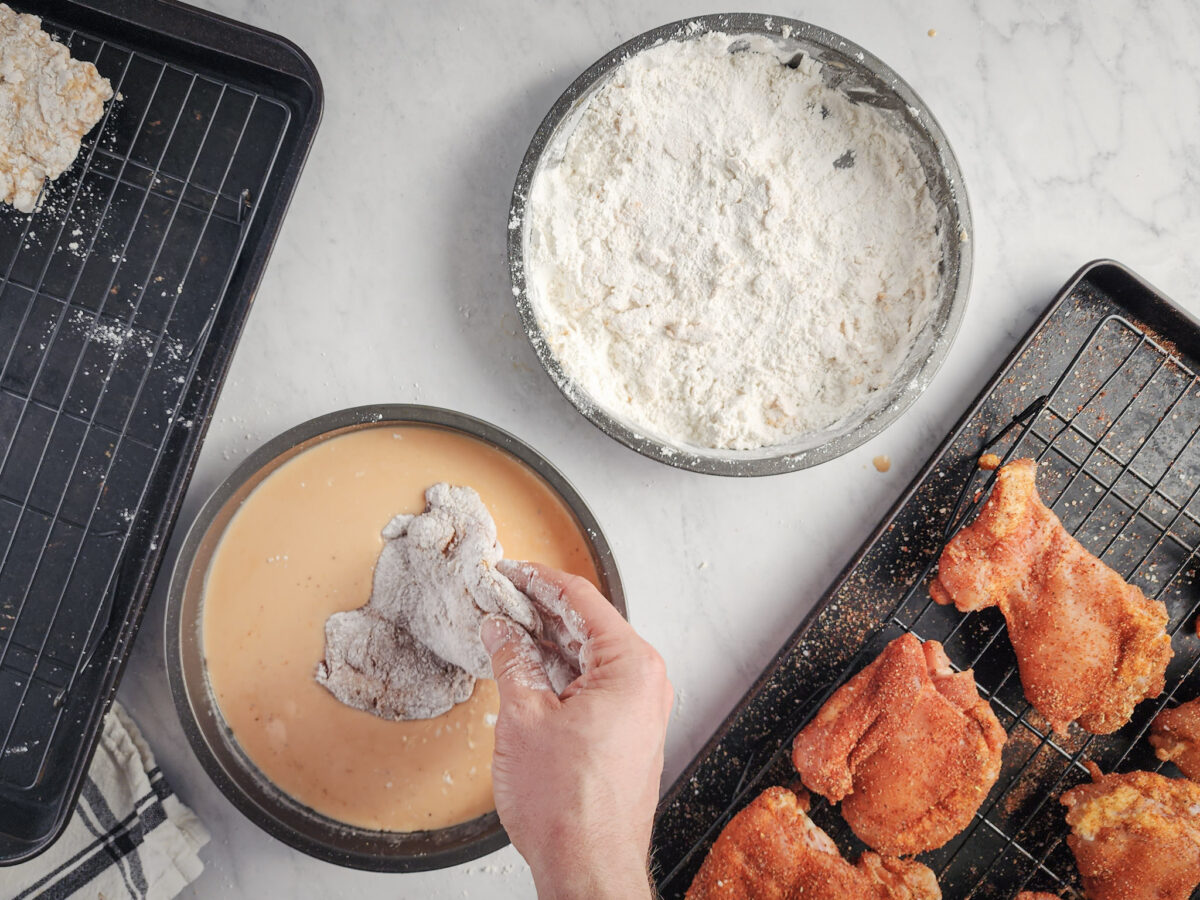 Adding breaded chicken to wet batter for frying.