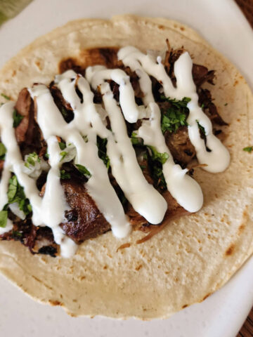 Mexican crema drizzled over a carnitas street taco.