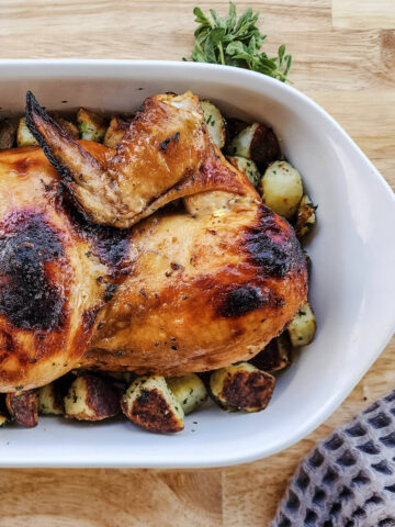 Whole roasted chicken served over potatoes