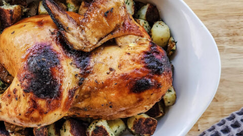 Whole roasted chicken served over potatoes