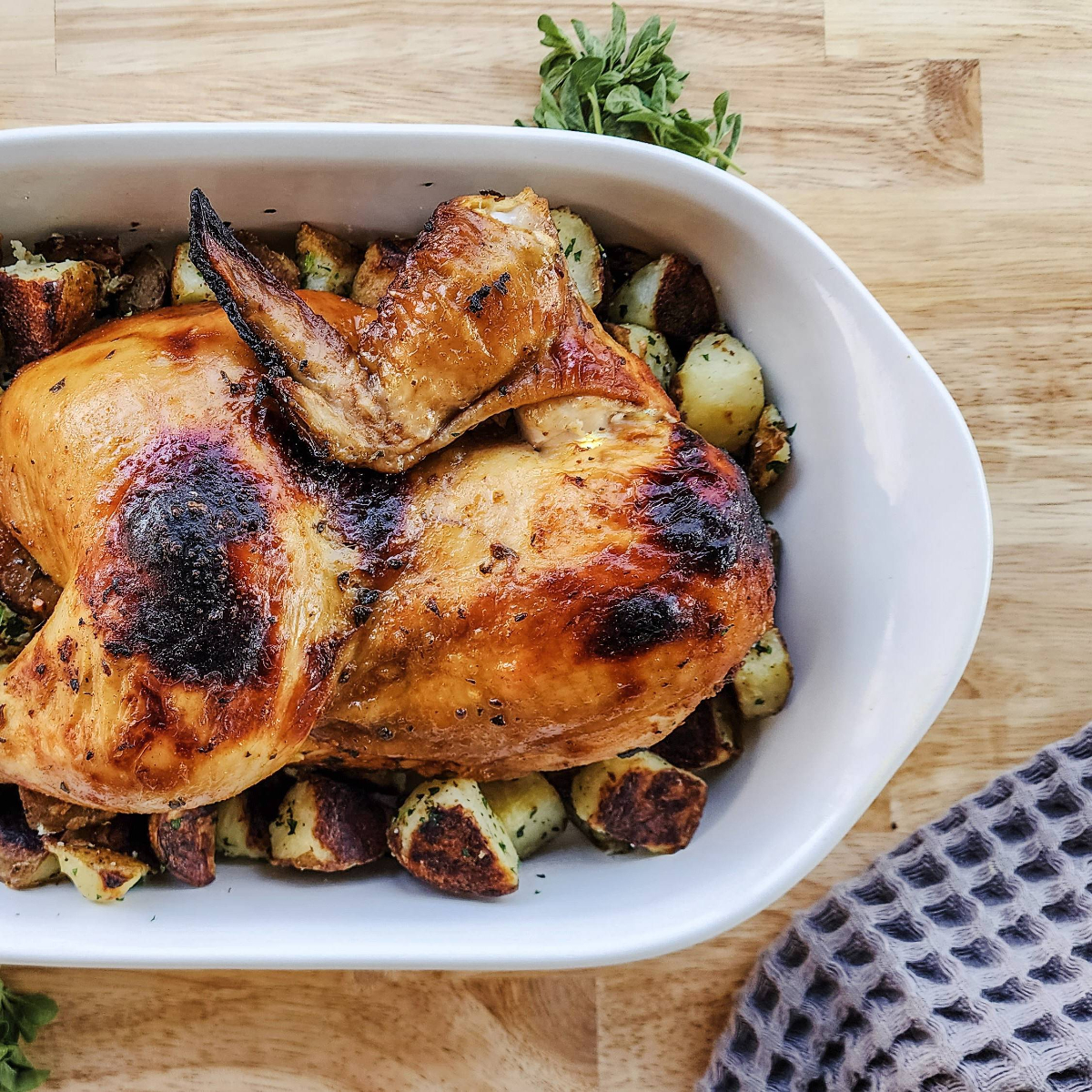 Whole roasted chicken served over potatoes