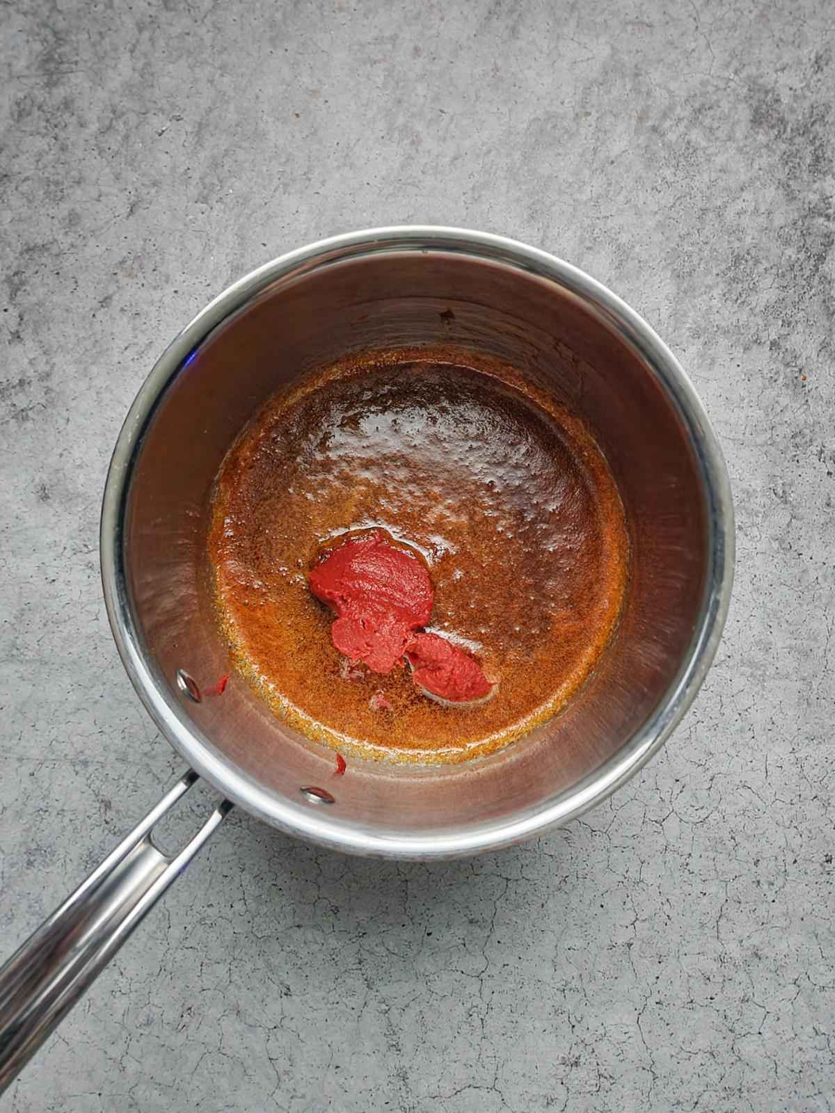 Add the tomato paste to the pan.