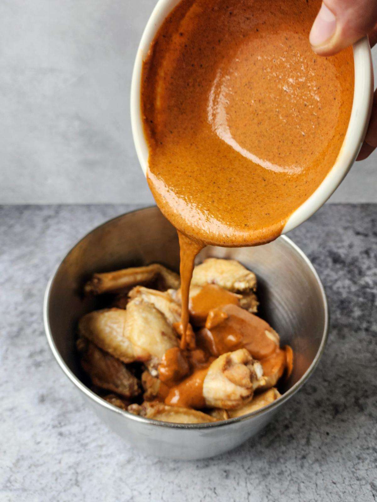 Tossing butter chicken hot wings in the sauce