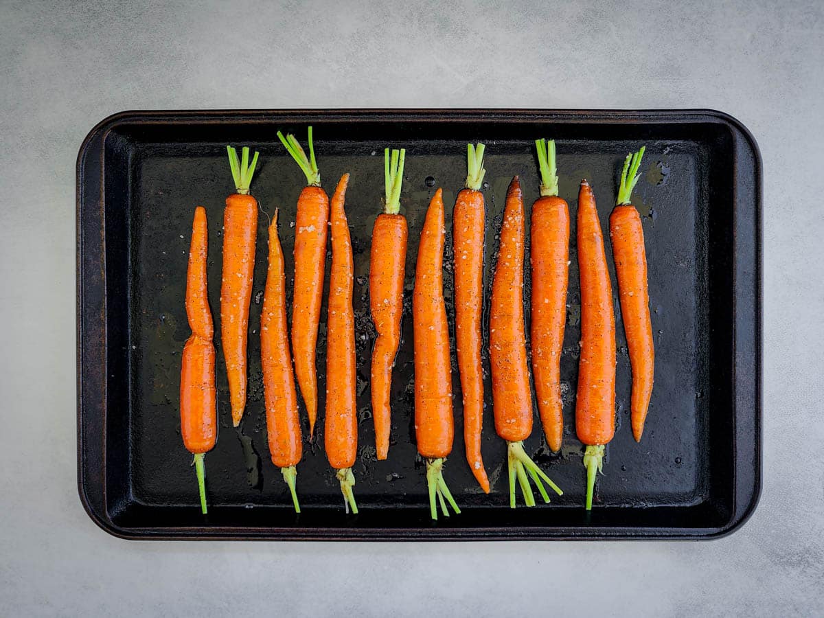 Carrots tossed in oil and salt and pepper, ready to be roasted