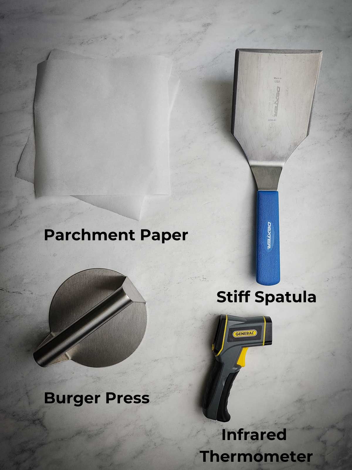 A picture of essential smash burger equipment: parchment paper, stiff spatula, burger press, and infrared thermometer.