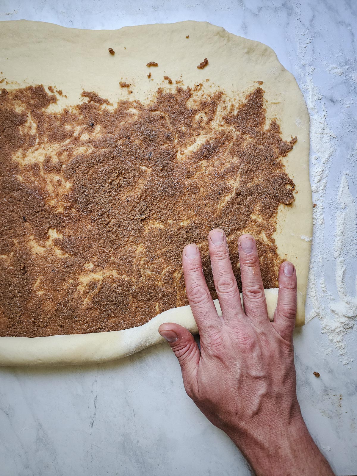 Chai-Spiced Cinnamon Roll - Assembly Step 4: Roll the dough into a tight log. Use a sharp knife or unflavored dental floss to trim approximately ½-inch off of each side to expose the chai-spiced filling.