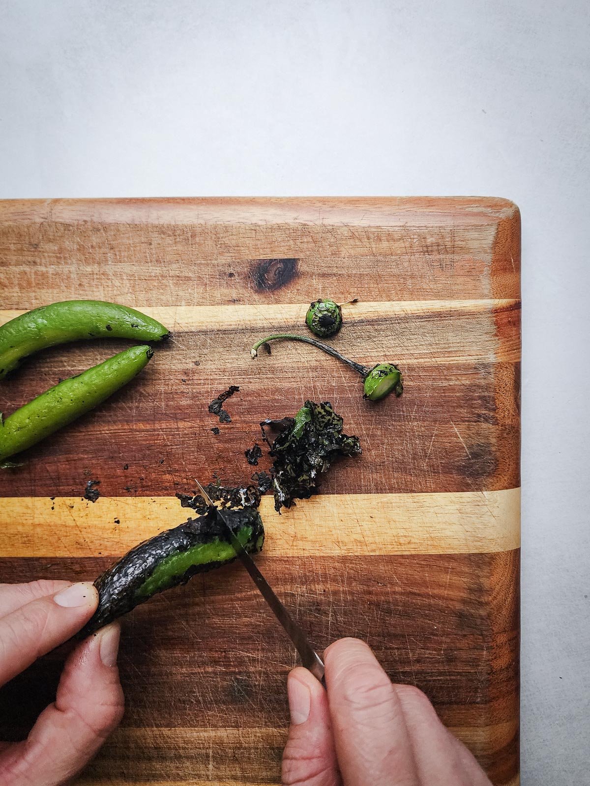 Fire-roasted blowtorch salsa step four: scrape the skins off the serrano peppers, halve them, and then remove the seeds.