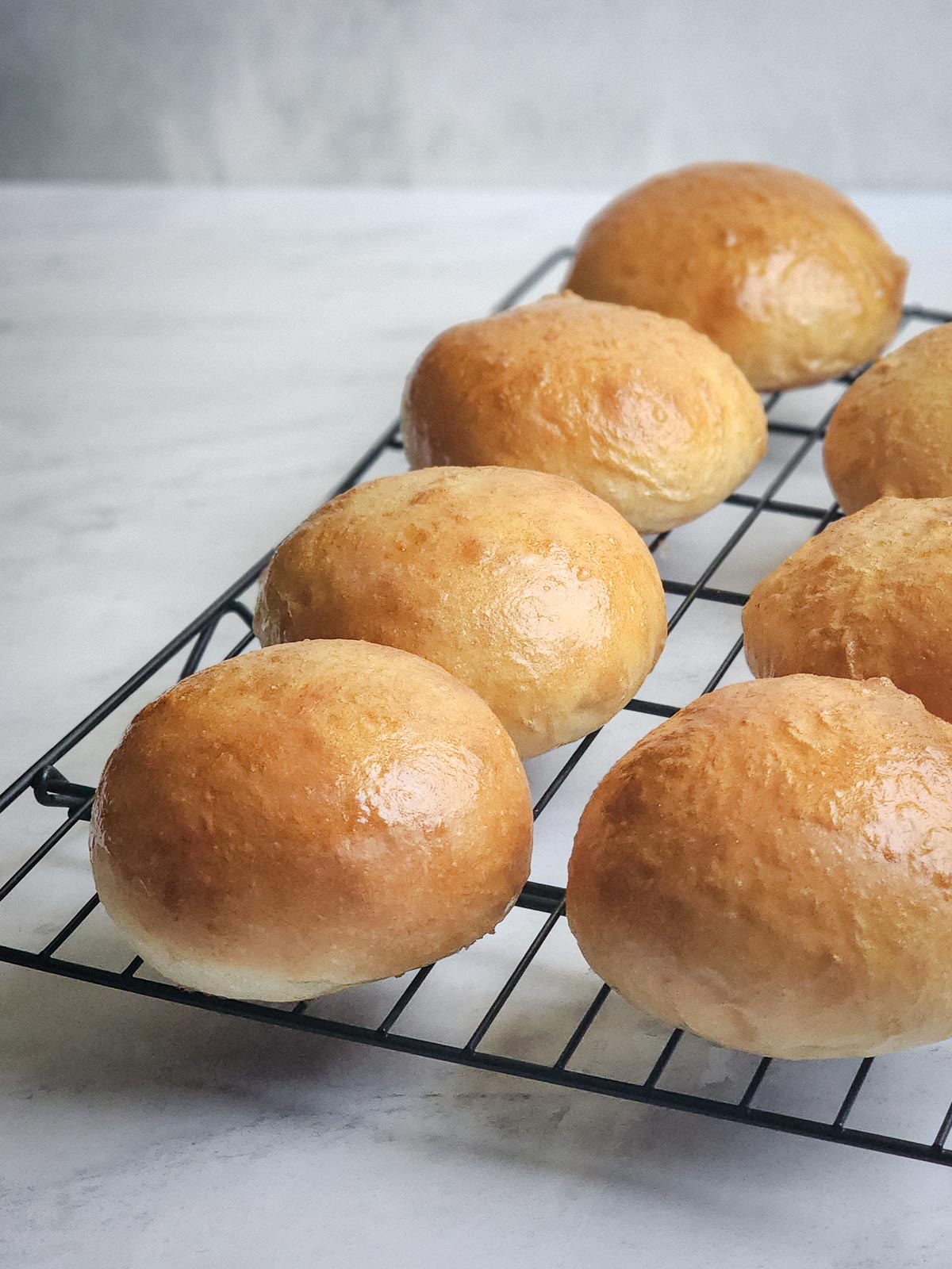 Ultimate Homemade Hamburger Buns on a wire cooling rack.