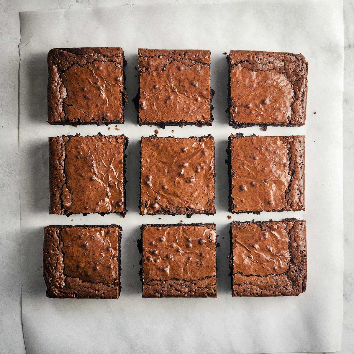 Homemade brownies on a piece of parchment paper.