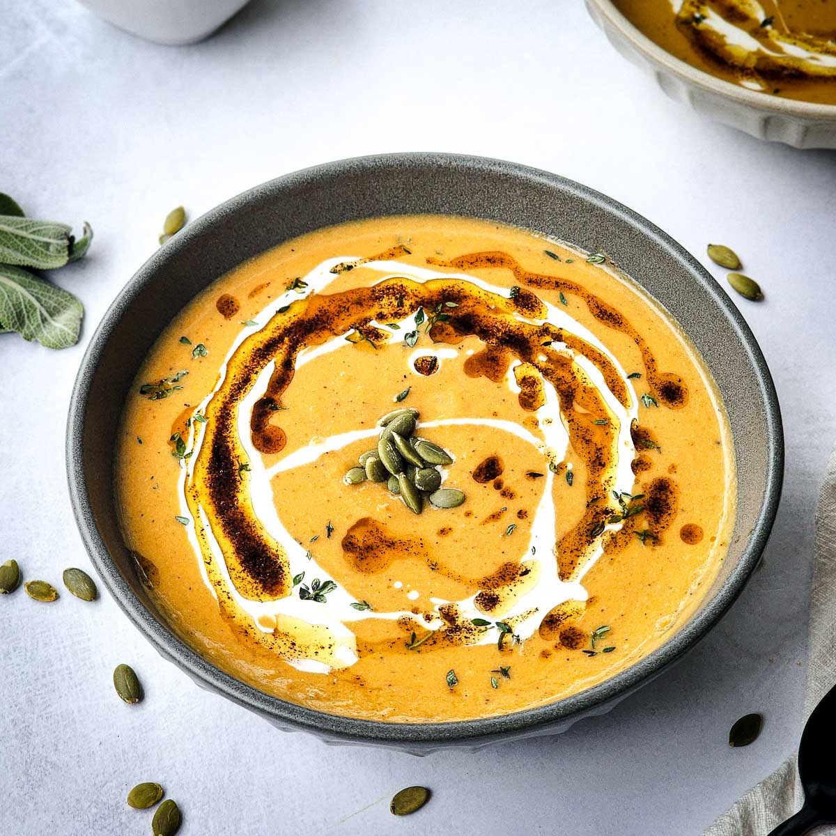 A bowl of roasted squash soup garnished with sage brown butter.
