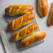 Freshly baked handmade sub rolls cooling on a wire rack.