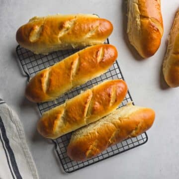 Freshly baked handmade sub rolls cooling on a wire rack.