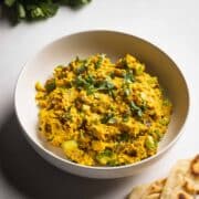 A bowl of curry chicken salad with rotisserie chicken served with naan and cliantro.