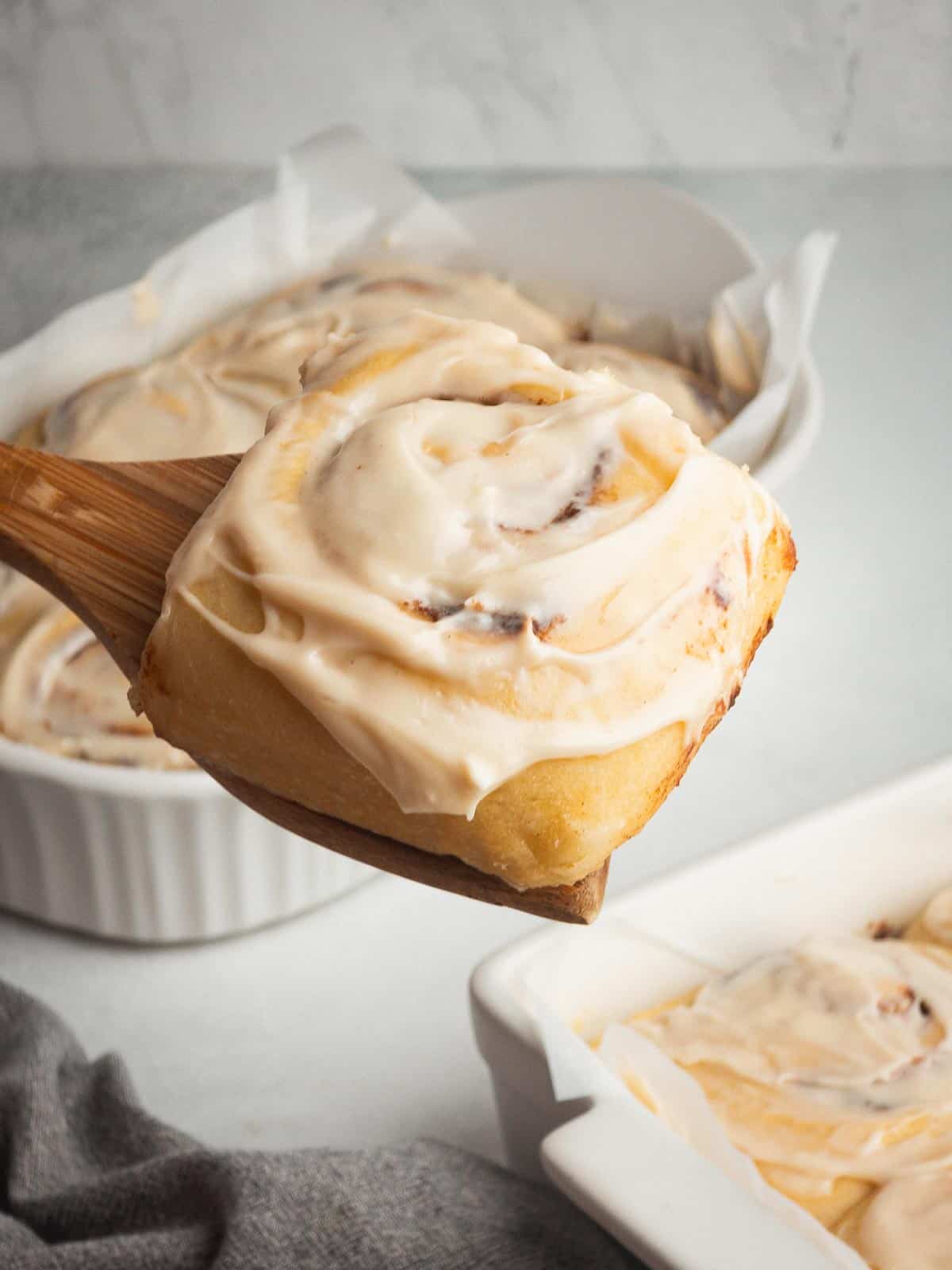 A cinnamon roll with cream cheese frosting being served.