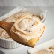 A cinnamon roll with cream cheese frosting being served.