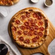 Pepperoni pizza made with cold ferment pizza dough on a wooden pizza peel.