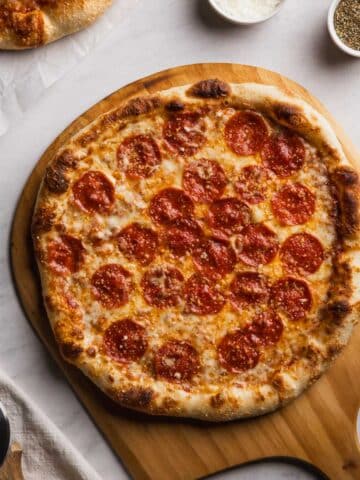 Pepperoni pizza made with cold ferment pizza dough on a wooden pizza peel.