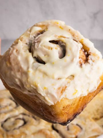 An orange glazed cinnamon roll being served.