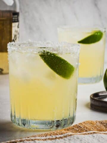 Two glasses with salted rims with Reposado Margaritas made with fresh lime juice.